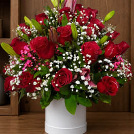 Red roses and lilies arranged in a white hatbox