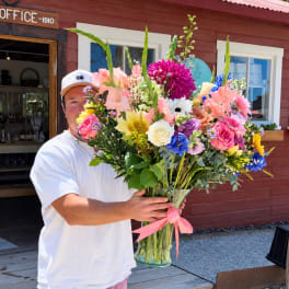 Large mixed bouquet in a glass vase with a pink ribbon