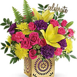 Pink roses and yellow lilies in a gold vase with a "celebrate" sign