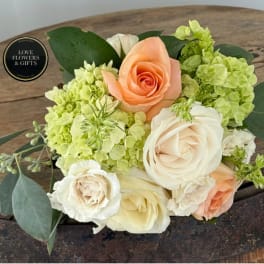 Peach and white roses with green hydrangeas in a compact bouquet