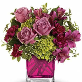 Pink roses and magenta flowers arranged in a square glass vase