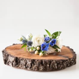 Small white and blue floral arrangement on a wood slice