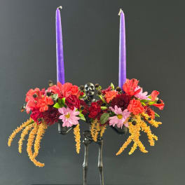 Floral arrangement with two purple taper candles on a skeleton stand