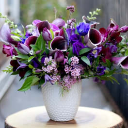 Purple and pink floral arrangement in a white textured vase