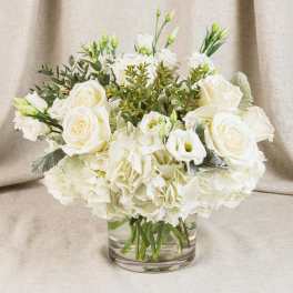 White roses and carnations arranged in a clear glass vase