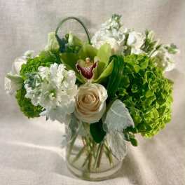 Green and white floral arrangement in a clear glass vase