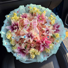 Pink rose bouquet with lilies, yellow filler flowers, and a ribbon bow