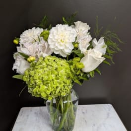 White and green floral arrangement in a clear glass vase
