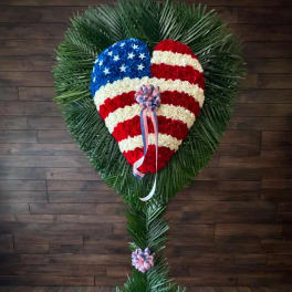 Heart-shaped floral tribute in red, white, and blue with ribbon accents