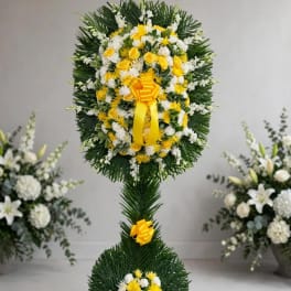 Tall standing floral wreath with yellow and white flowers and yellow ribbon