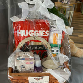 Gift basket with baby items wrapped in clear cellophane and a white bow
