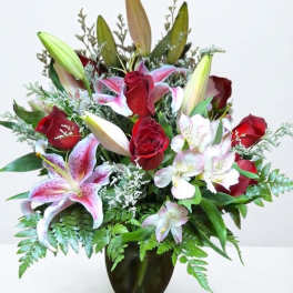 Bouquet of red roses and pink lilies in a dark glass vase