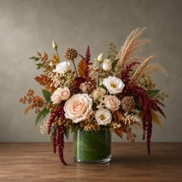 Autumn floral arrangement with blush and white roses in a glass vase