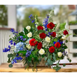 Basket arrangement of red and white roses with blue flowers