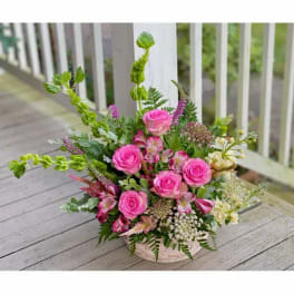 Pink roses and mixed flowers arranged in a low basket