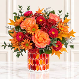 Orange and red floral arrangement in a patterned vase