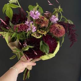 Handheld bouquet of burgundy, pink, and lavender flowers