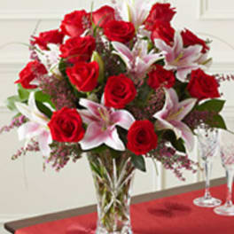 Red roses and pink lilies arranged in a clear glass vase