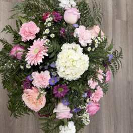 Pink and white mixed flower bouquet with greenery on a wood floor