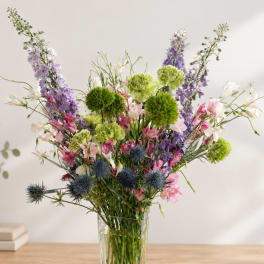 Mixed bouquet in a clear glass vase with purple, pink, white, and green flowers