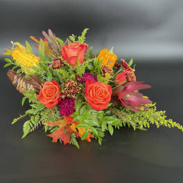 Autumn floral arrangement with orange roses and gourds in a woven basket