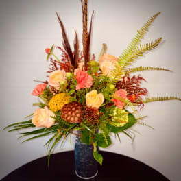 Peach roses and coral carnations in a tall blue vase