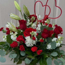 Red roses and white lilies in a tall vase with a red heart topper
