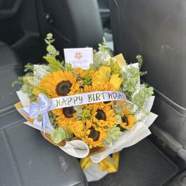 Sunflower bouquet with yellow roses and a birthday ribbon in a car seat