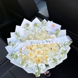 Cream rose bouquet with white flowers and a satin ribbon reading "Miss to Mrs"