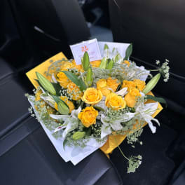 Yellow roses and white lilies in a wrapped bouquet