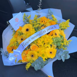 Yellow bouquet with gerbera daisies and roses wrapped in pale blue paper