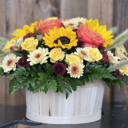 Mixed bouquet in a white ribbed container with sunflowers and roses