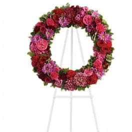 Circular floral wreath on a white easel with pink and red flowers