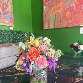 Mixed bouquet in a clear glass vase with pink, orange, purple, and white flowers