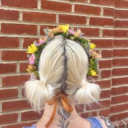 Flower crown on a blonde person with pink and yellow blooms