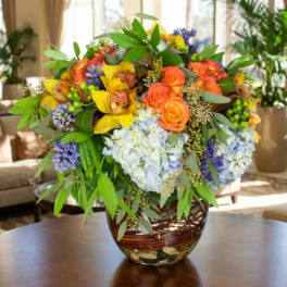 Colorful bouquet of roses, orchids, and hydrangeas in a glass vase