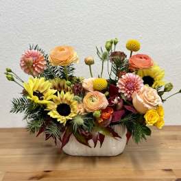 Mixed bouquet of sunflowers, roses, and dahlias in a white ceramic vase