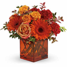 Orange and red flowers arranged in a square amber vase