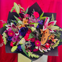 Colorful mixed bouquet with lilies, chrysanthemums, and carnations in black wrap