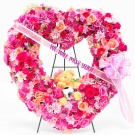 Heart-shaped floral wreath with pink roses and a ribbon message