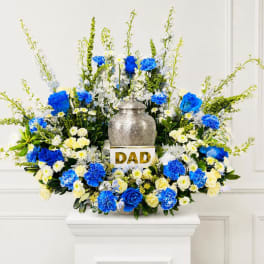Blue and white floral arrangement around a silver urn with a "DAD" sign