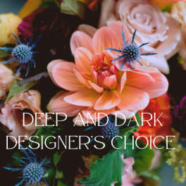 Close-up of a deep-toned mixed bouquet with peach dahlia, roses, and blue thistle flowers