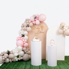 Pastel balloon arch with small floral accents around a baby shower backdrop