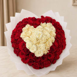 Heart-shaped bouquet of red and cream roses wrapped in white paper