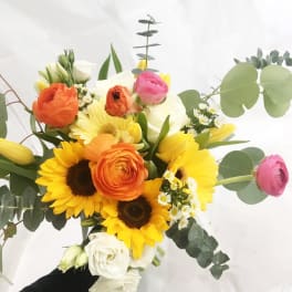 Mixed bouquet with sunflowers, roses, and ranunculus in white and yellow.