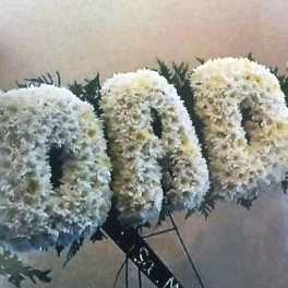 White floral letters with dark greenery accents