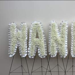 White floral letters spelling "NANDA" on black stands