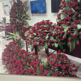 Large red rose funeral sprays and casket pieces arranged indoors