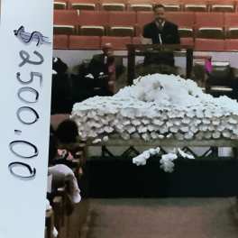 Large white floral casket spray in a church setting