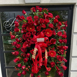 Large red sympathy standing spray with roses and gerbera daisies on an easel